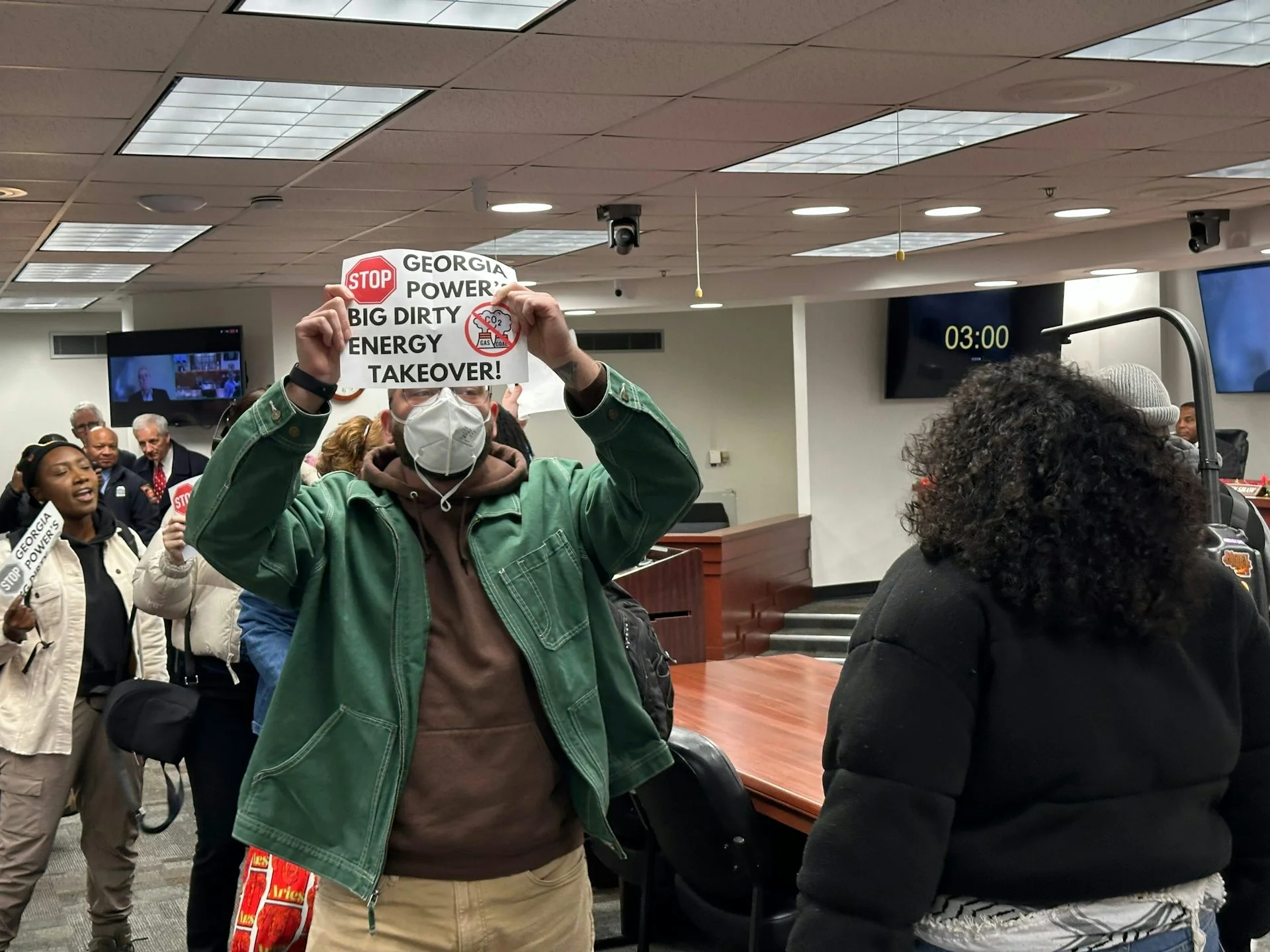 Anti-data center protestors, holding signs, are escorted out of a Georgia Public Service Commission meeting in Atlanta.