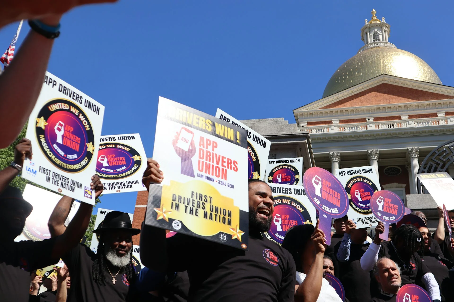 Rideshare drivers hold signs at a rally outside the Massachusetts State House in Boston to celebrate the establishment of their first-ever union in the U.S.