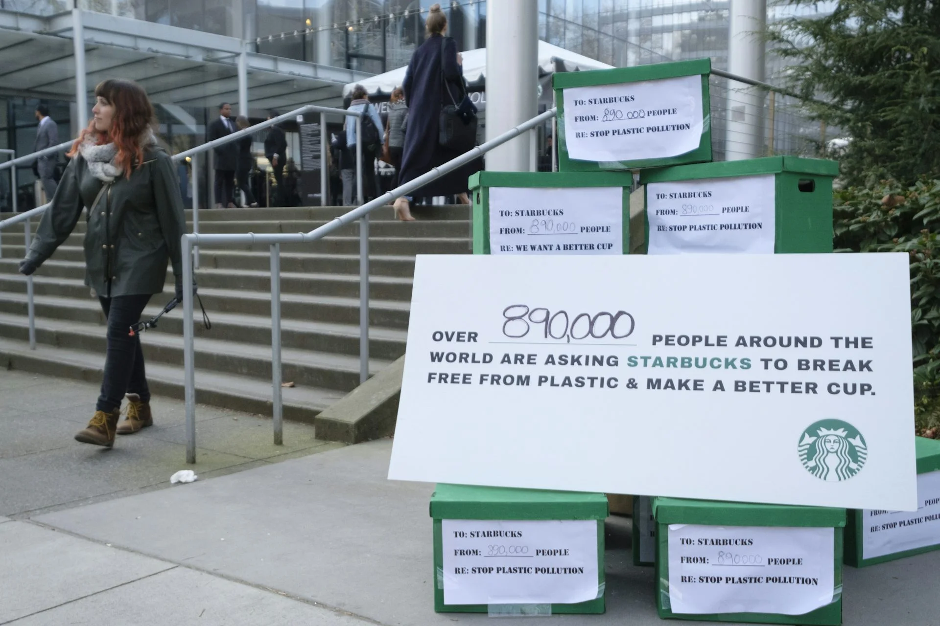 A woman passes a display set up by activists takin aim at Starbucks packaging policies.