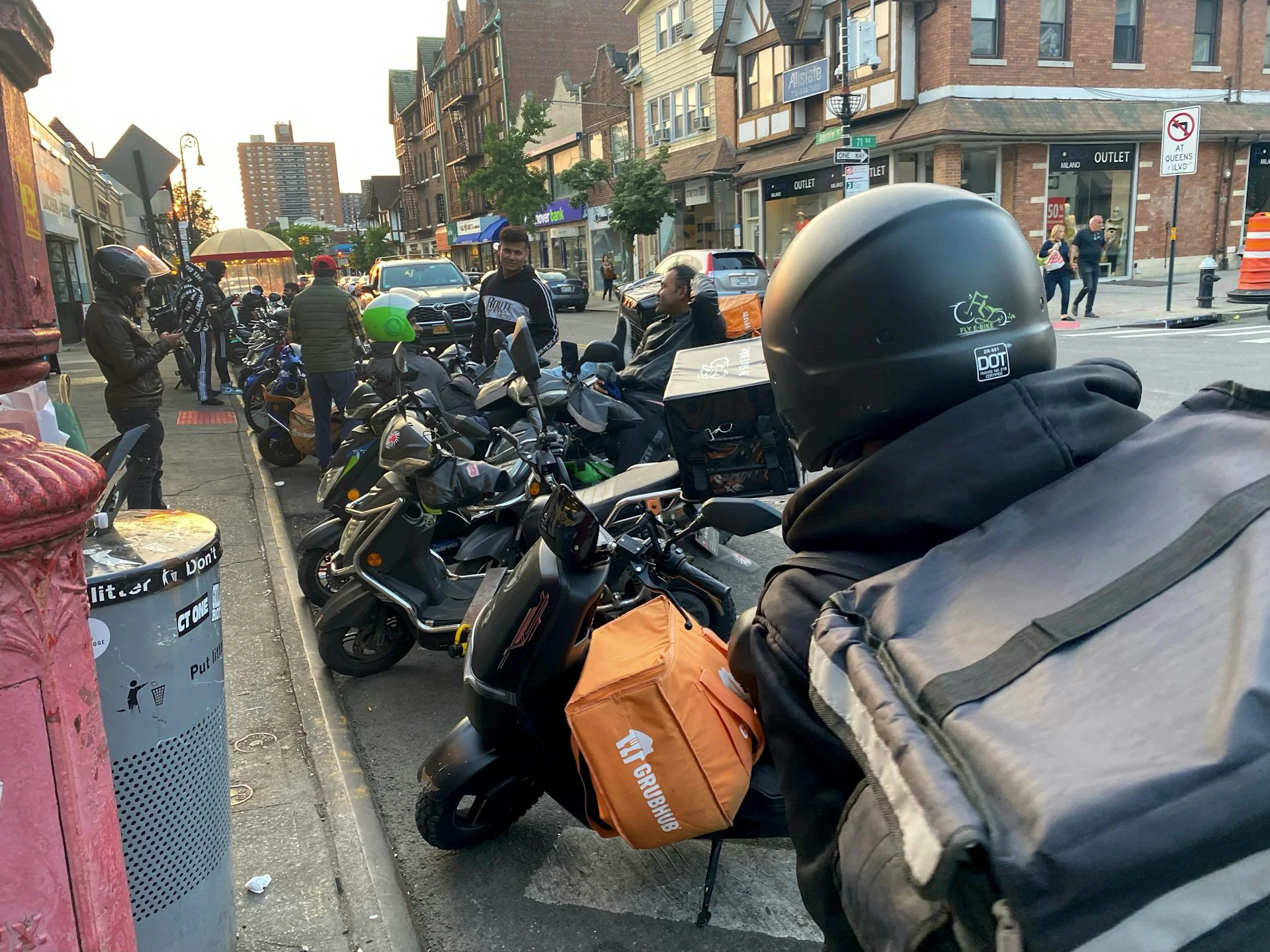 A big group of delivery workers seen on a street with their motorcycles.