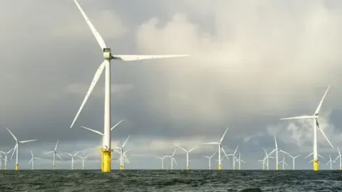 PA Media An offshore windfarm set against a cloudy sky