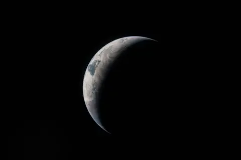 NASA A cresent view of the Earth with sunlight falling on th eright side of its surface in the blackness of space.